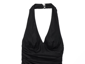 Detail view of the black halter dress featuring textured fabric and pleated waist design