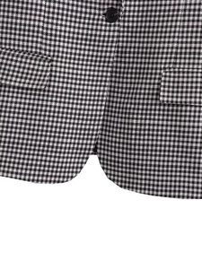 Detail of houndstooth blazer showing flat flap pockets, black button and curved hemline