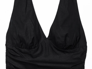 Detailed view of black halter dress featuring textured woven fabric and pleated waist details