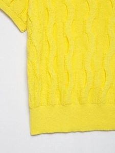 Close-up of vibrant yellow knitted sweater showing vertical wave textured pattern