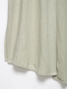 Close-up of light green linen dress hem with detailed stitching and natural fabric texture
