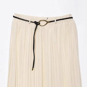 Jupe midi plissée beige en mousseline avec ceinture fine noire et boucle dorée élégante