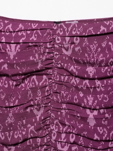 Close-up of purple abstract floral print fabric with detailed ruching and stitching detail
