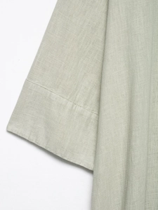 Detailed close-up showing the natural linen fabric texture and stitching on light green cuff