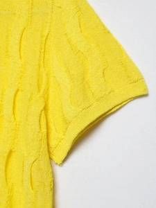 Detail of bright yellow knit sweater showing textured hollow-out patterns and fabric finish