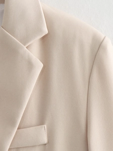 Detail view of beige blazer featuring notched lapels and high-quality twill fabric texture
