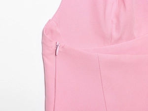 Détail d'une fermeture éclair invisible latérale sur une robe rose en tissu uni