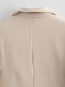 Detailed close-up of the notched lapel and high-quality back stitching on a beige blazer