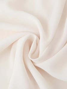 Vista macro del tessuto chiffon bianco crema con volant morbidi e trama fine drappeggiata