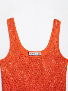 Macro detail of vibrant orange knitted tank top with shimmering sequins and wide straps