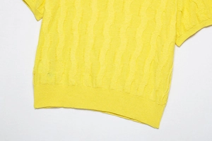 Detailed macro shot of lemon yellow knit top featuring wavy texture and ribbed hem details