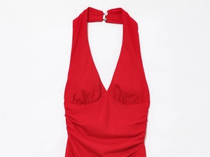 Detail view of red halter dress featuring deep V-neckline and gathered pleats on smooth fabric