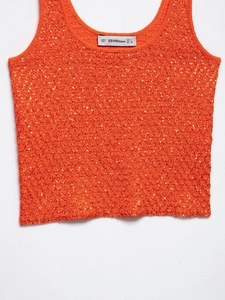 Detail shot of shimmering orange sequined knit top with inner brand and size label