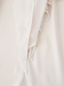 Dettaglio degli strati di volant color crema e delle cuciture fini sul top in chiffon