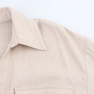 Detailed macro view of beige cotton-linen fabric texture and stitching on the shirt collar