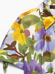 Detail of floral print on V-neck dress with vibrant yellow and lilac digital patterns