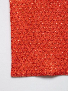 Detail of orange knitted fabric with golden sequins and diamond texture on women's top