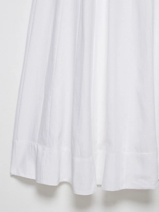 Detailed macro view of the pleated white cotton midi dress hem with wide stitch detailing