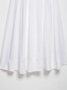 Detailed close-up of white midi dress hem with pleated texture and stitching