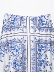 Close-up of elegant white maxi skirt featuring blue floral prints and vintage border patterns