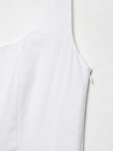 Detail view of the seamless invisible zipper and textured white linen fabric on the midi dress