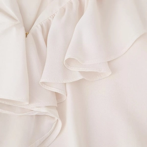 Close-up of elegant ivory ruffled neckline blouse with delicate gold button detail