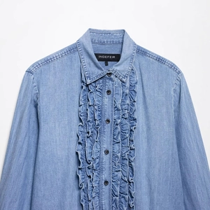 Women's light blue ruffled denim shirt with black buttons and loose fit style
