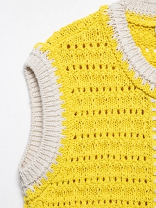 Dettaglio gilet all'uncinetto giallo e beige con scollo rotondo e motivo floreale traforato
