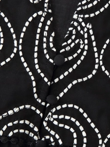 Detailed macro view of white embroidery and fabric covered buttons on a black linen shirt