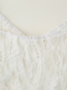Detail of elegant white lace dress neckline featuring intricate hollow-out floral patterns