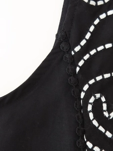 Detail of black summer top with white embroidery and 3D floral decorative edges