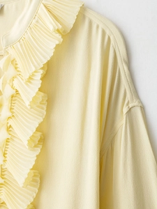 Detailed view of elegant ruffled pleats and texture on light yellow women blouse