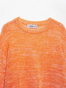 Detail of multi-color orange and white space dye knit fabric and round neckline texture