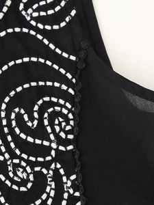 Close-up of bohemian black fabric with white wave embroidery and delicate lace trim