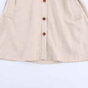 Close-up of beige cotton linen shirt dress with brown wooden buttons and side pockets