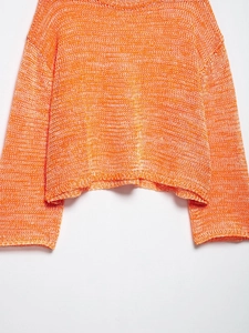 Close-up of orange and white mixed loose hollow knit texture on a cropped sweater