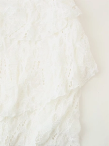 Close-up of elegant white layered lace dress showing floral crochet and ruffle details