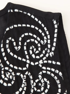 Close-up of white contrast embroidery with spiral stitching patterns on black fabric