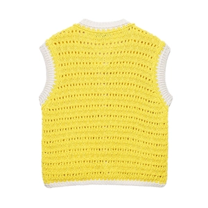 Dettaglio del gilet in maglia traforata gialla con finiture a costine bianche su collo e orlo