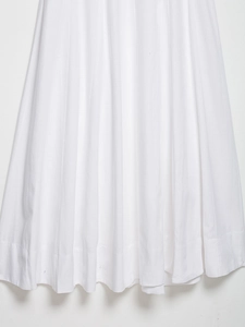Detailed macro view of the pleated hem and premium cotton texture of the white midi dress