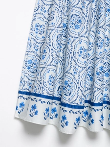 Détail de l'imprimé floral bleu et de l'ourlet rayé sur une jupe midi en coton blanc