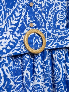 Détail de robe en dentelle anglaise bleue avec boutons en bois et boucle de ceinture en paille