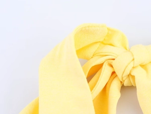 Detailed view of the elegant bright yellow halter dress with a knotted bow design