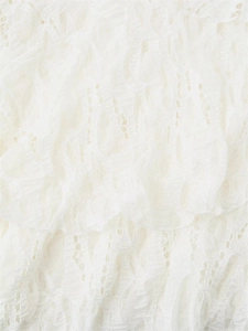 Detailed macro view of white layered ruffles with intricate lace hollow texture