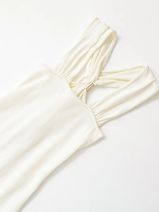 Detail of ivory knit top showing halter neckline with cross-pleats and gold metal buckle