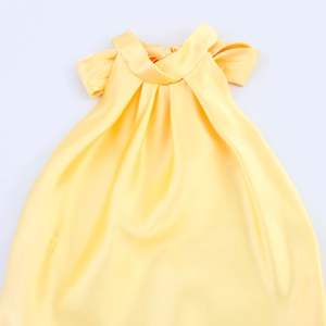 Detail view of bright yellow satin halter dress showing elegant pleated neckline texture