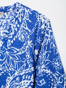 Gros plan détaillé de la broderie anglaise bleue et blanche sur une robe en V