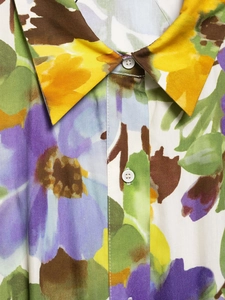 Close-up of colorful floral print fabric with delicate white buttons on a summer blouse