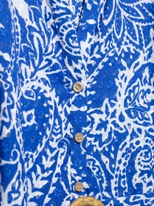 Détail de broderie anglaise bleue avec bouton en bois et boucle de ceinture tressée