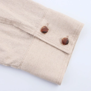 Detail of beige cotton linen sleeve with double stitching and marble texture buttons